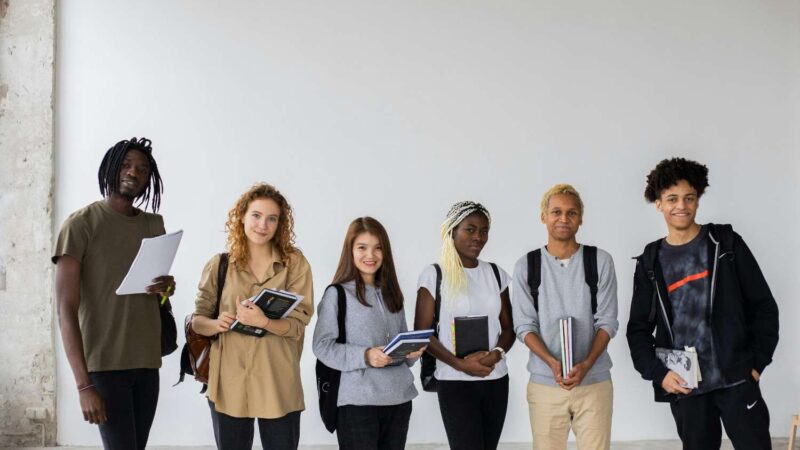 Diverse group of students standing with books and backpacks