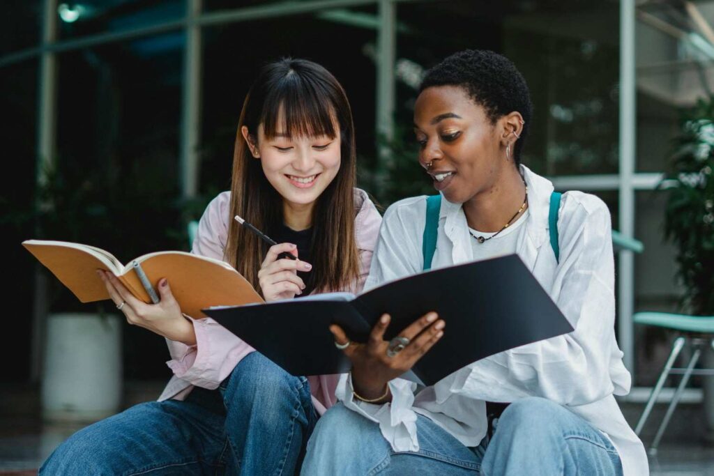 Multiracial female students studying together outside