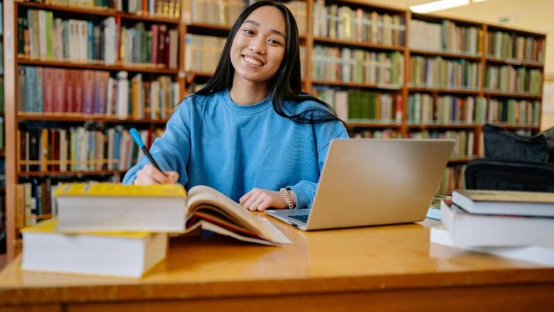 Woman in Blue Long Sleeve Shirt Sitting at the Table Smiling
