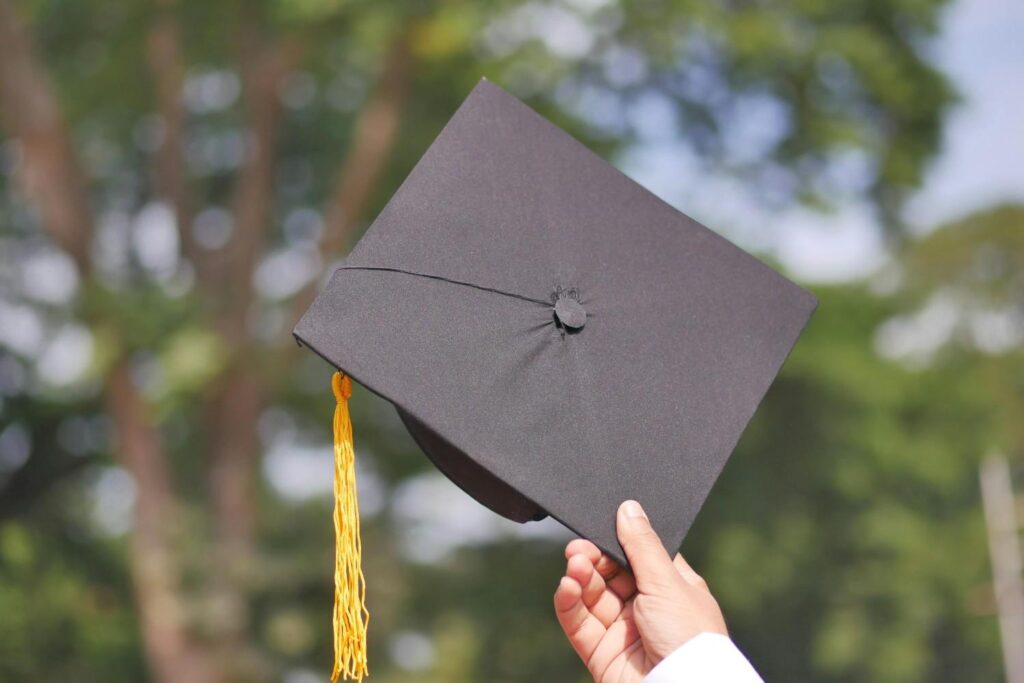 A hand holding an academic cap with a string