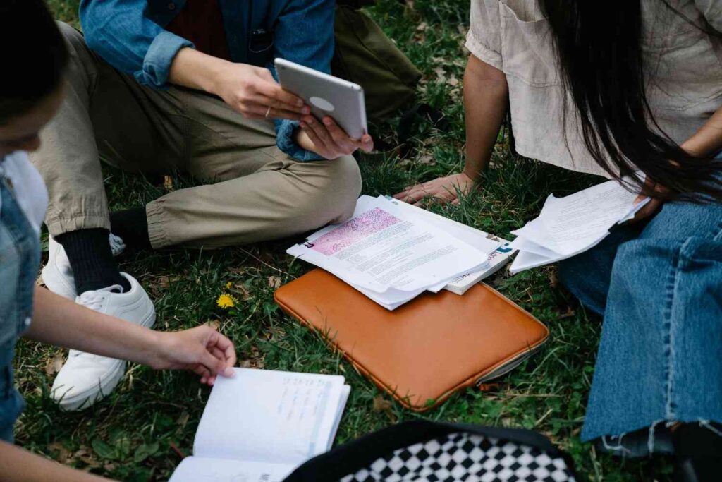 A group of people sitting on grass studying