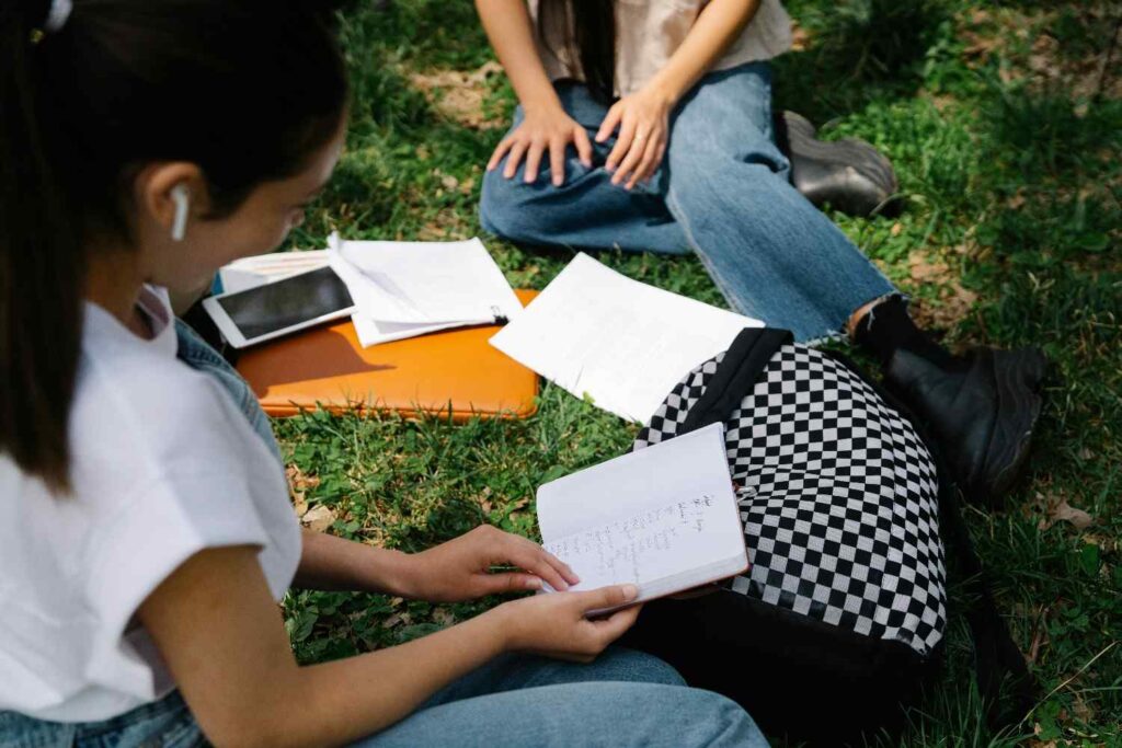 Two students studying together outdoors on a sunny day