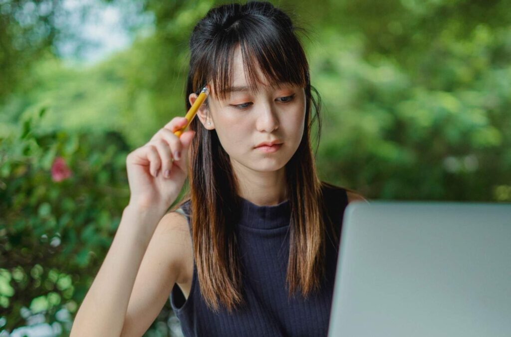 Focused young woman studying outdoors using a laptop